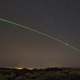 A visible green laser shines from ESA’s Optical Ground Station (OGS).